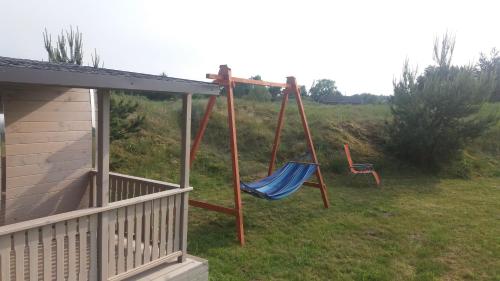two swings in a yard next to a house at Gaišie in Jūrmalciems