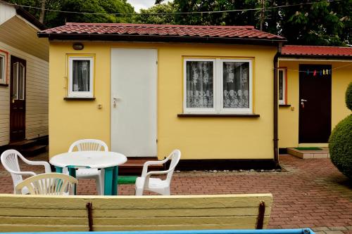a small yellow house with a table and chairs at Domki letniskowe U GOSI in Trzęsacz