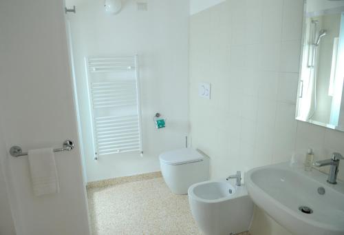 a white bathroom with a toilet and a sink at Contrada Cappuccini in Ginosa