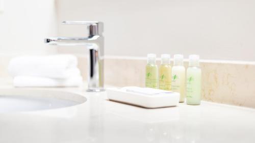 a bathroom sink with two bottles of detergents on it at Hotel Rimouski in Rimouski