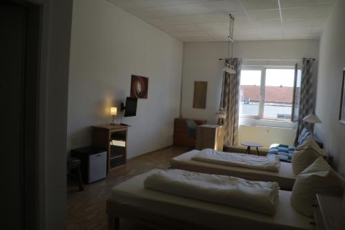 - un salon avec deux lits et une fenêtre dans l'établissement Pension Isartal, à Geretsried
