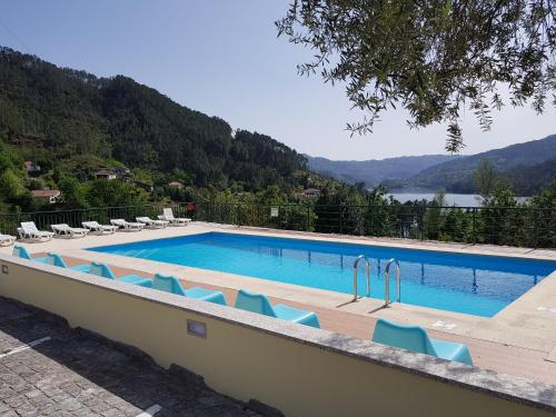 una piscina con sillas y vistas al lago en Hotel Lagoa Azul do Geres, en Gerês