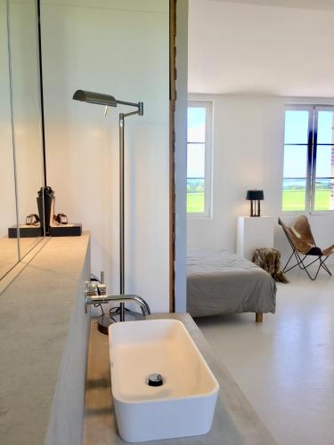 - une salle de bains blanche pourvue d'un lavabo et d'un lit dans l'établissement Galerie, Tumulus de la Hogue, à Fontenay-le-Marmion