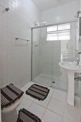 a white bathroom with a shower and a sink at CASA TEMPORADA TUCO E TUCA in Ubatuba