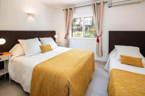 カルヴォエイロにあるVilla Tara, Heated private pool, short walk to to town & beachのベッド2台と窓が備わるホテルルームです。