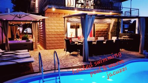a swimming pool in front of a house with a restaurant at Villa Summer dream with heated pool, sauna and jacuzzi in Malinska