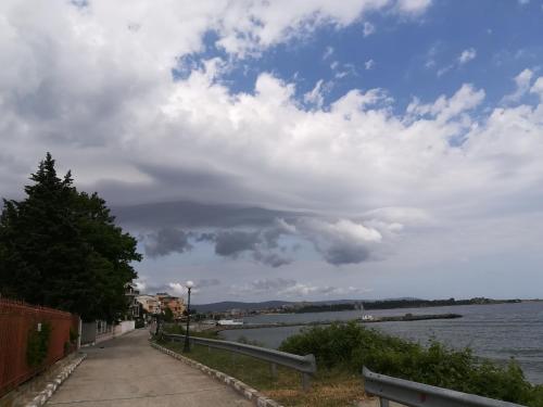 a path next to a body of water with a cloudy sky at Hotel Diva in Ravda