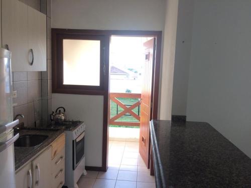 uma cozinha com um lavatório e uma porta para um quintal em Apartamento em Residencial Riviera em Florianópolis