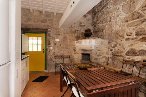 a stone kitchen with a wooden table and a yellow door at Eido Da Portela - Casa De Campo in Carregadouro