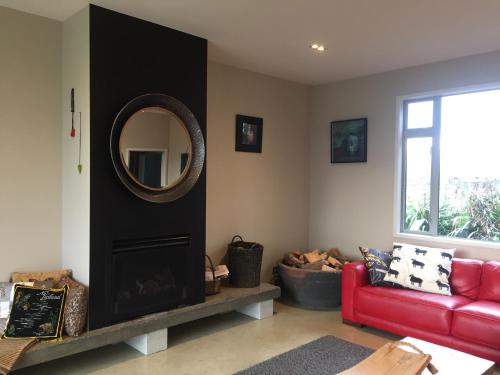 a living room with a red couch and a mirror at Appleby House & Rabbit Island Huts in Mapua