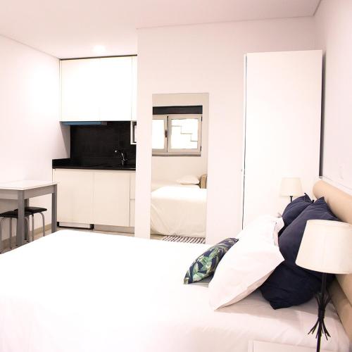 a bedroom with white walls and a bed with a mirror at Avenida in Praia de Mira