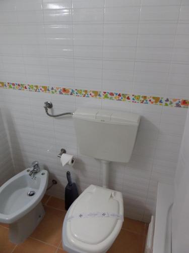 a white bathroom with a toilet and a sink at Mirachoro Albufeira in Albufeira
