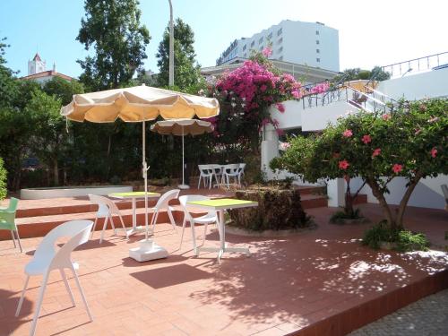 a patio with tables and chairs and an umbrella at Mirachoro Albufeira in Albufeira