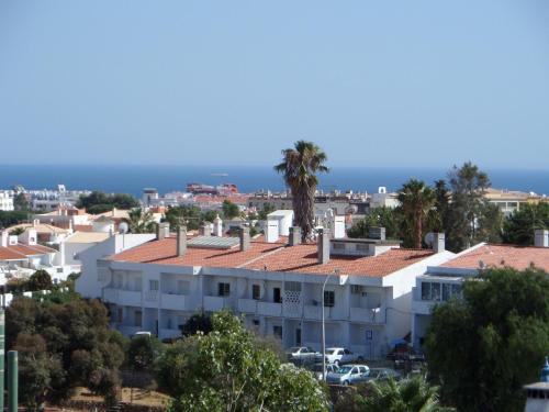 a white building with palm trees and the ocean in the background at Mirachoro Albufeira in Albufeira
