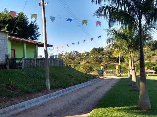 a road with flags and a house and palm trees at Pousada & Pesca Esportiva Fazolin in Socorro