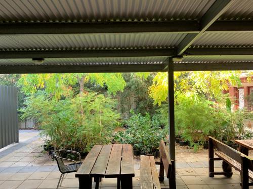 einen hölzernen Picknicktisch unter einer Markise auf einer Terrasse in der Unterkunft CROWN CENTRAL BUSINESS DISTRICT MOTEL - NO UNDER 18s in Bendigo