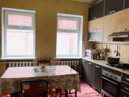 a kitchen with a table and two windows at Mukarama-Apa in Bishkek