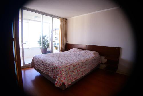 1 dormitorio con cama y ventana grande en Departamentos Alto Libertad, en Viña del Mar