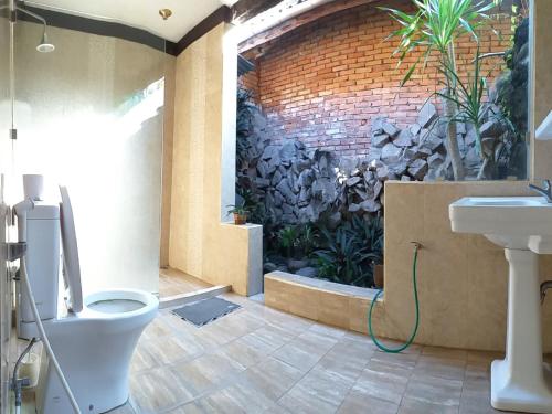 baño con aseo y pared con plantas en Puri Asri Bungalow Ubud, en Ubud