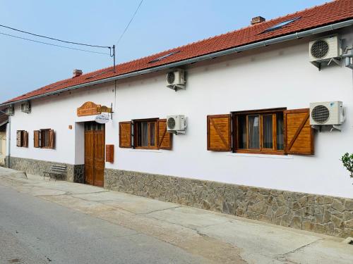 a white house with wooden windows and a street at Casa "La Moara din Grădină" in Eftimie Murgu