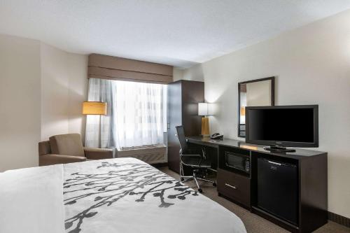 a hotel room with a bed and a flat screen tv at Sleep Inn DeWitt - Lansing North in DeWitt