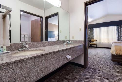 Quality Inn & Suites في ماكوك: حمام به مغسلتين ومرآة كبيرة