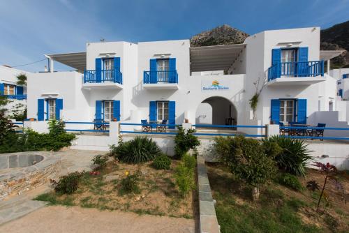 a large white building with blue windows and a courtyard at Boufounis Studios in Kamarai