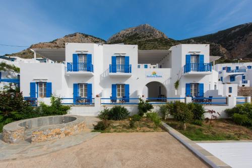 a white building with blue windows and mountains in the background at Boufounis Studios in Kamarai
