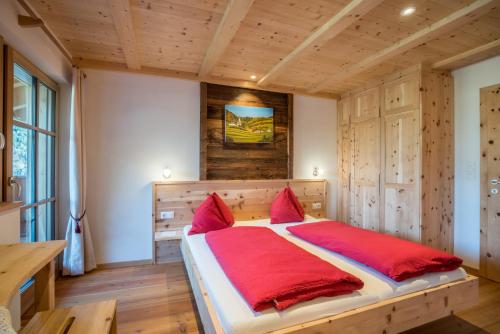 a bedroom with a large bed with red pillows at Hofer Hof in Feldthurns