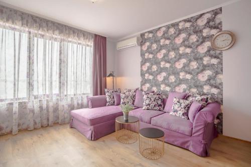 a living room with a purple couch and a floral wall at Gardenia Beach Palace Aparthotel in Pomorie