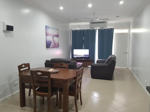 a living room with a table and chairs and a television at Prestige Apartments - Solomon Islands in Honiara