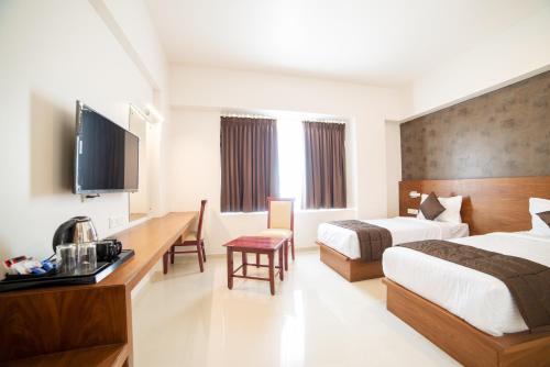 a hotel room with two beds and a desk at Heritage Inn in Mysore