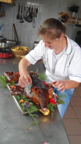 a woman preparing a roasted turkey on a counter at Pensiunea Popasul Iancului in Mărişel