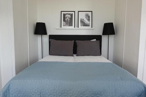 a bedroom with a blue bed with two black lamps at Waterside Mariestad in Mariestad