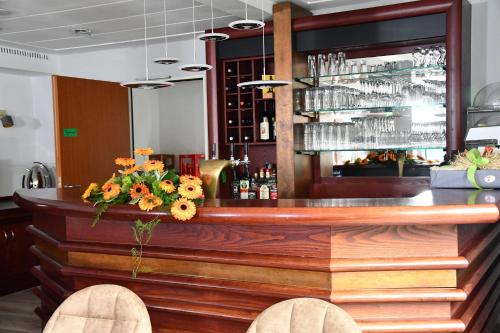 a bar in a restaurant with flowers on the counter at LANDHAUS LENGEDE Hotel in Lengede