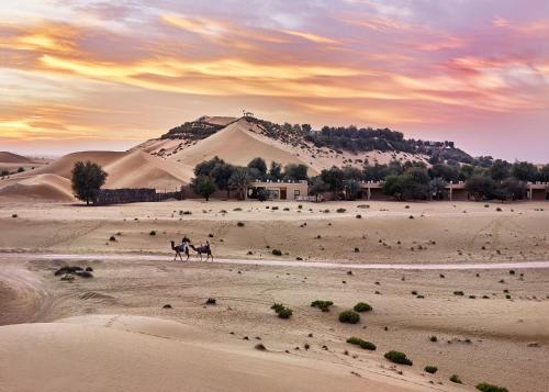 a couple of people riding horses in the desert at Telal Resort Al Ain in Al Ain