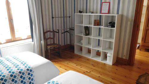 ein weißes Bücherregal in einem Zimmer mit einem Bett in der Unterkunft La Cle des Sens in Le Faubourg