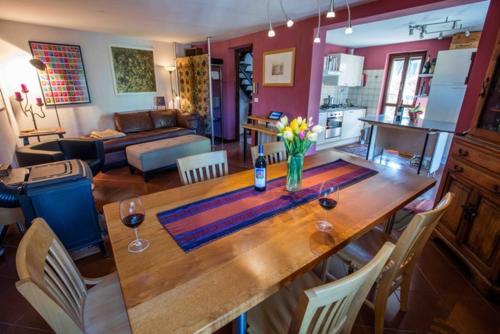 una cocina y una sala de estar con una mesa de madera con flores. en Casa Centro Storico, en Neive