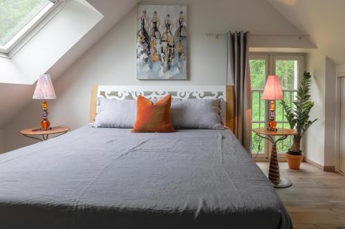 a bedroom with a bed with orange pillows and two lamps at Country House - La Charbonnière in Continvoir