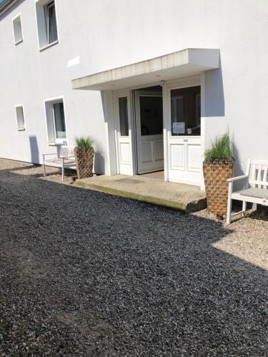 a white building with two benches in front of it at Hotel & Ferienunterkünfte Hus Seeblick in Fehmarn