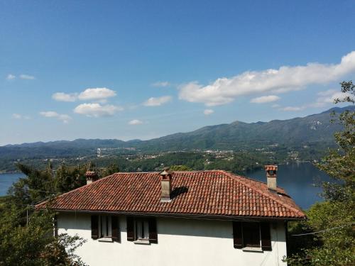 a white house with a red roof and a lake at Terrazza sul lago in Ameno