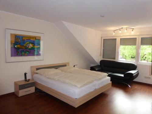 a bedroom with a bed and a couch and a chair at Hotel Am Sportpark in Duisburg