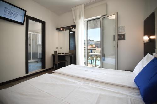 a bedroom with a large white bed and a balcony at Hotel Bristol in Caorle