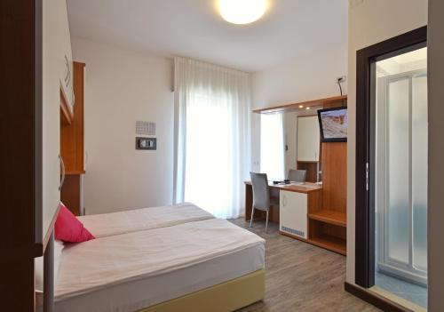 a bedroom with a bed and a desk with a computer at Hotel Bristol in Caorle
