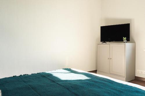 a bedroom with a bed and a flat screen tv at Greenhouse Apartments in Jūrmala