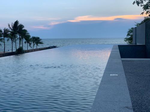 a swimming pool with the ocean in the background at Ana Anan Resort & Villas Pattaya in Na Jomtien