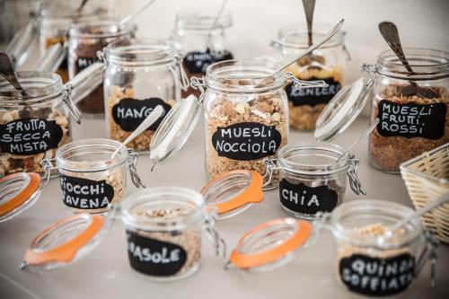 a table topped with jars filled with different types of food at Hotel Virginia in Diano Marina