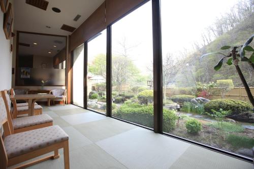a room with a large window with a view of a garden at Kashoutei Hanaya in Noboribetsu