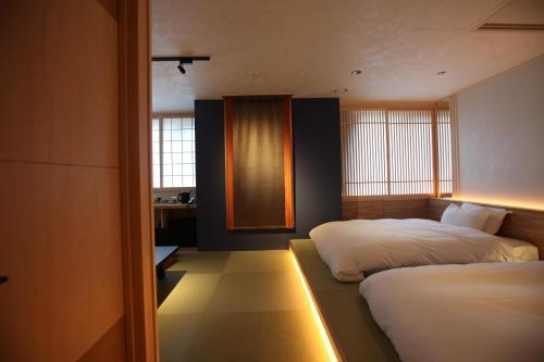 a bedroom with two beds and a desk in it at Kashoutei Hanaya in Noboribetsu
