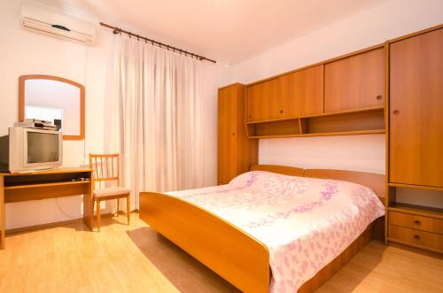 a bedroom with a bed and a desk and a tv at Rooms Mozara in Trsteno